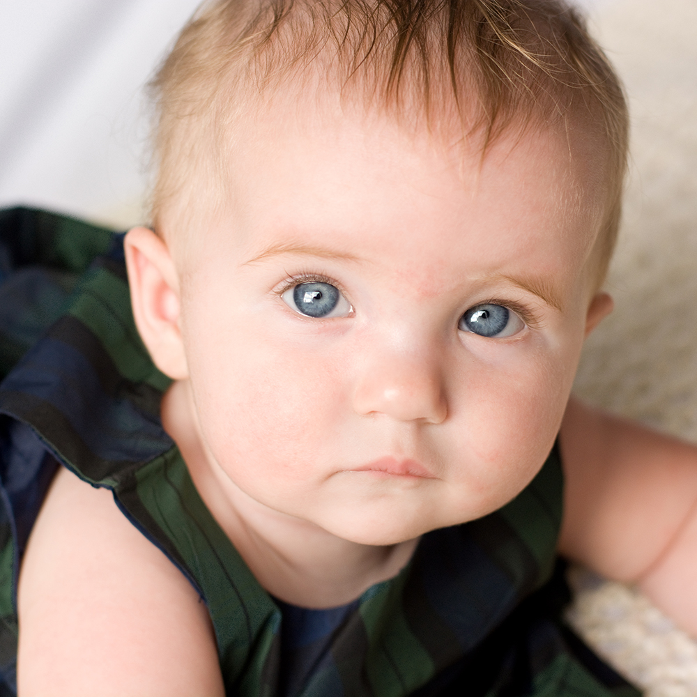 Close photo of a baby looking up at the camera by Jessika Digital